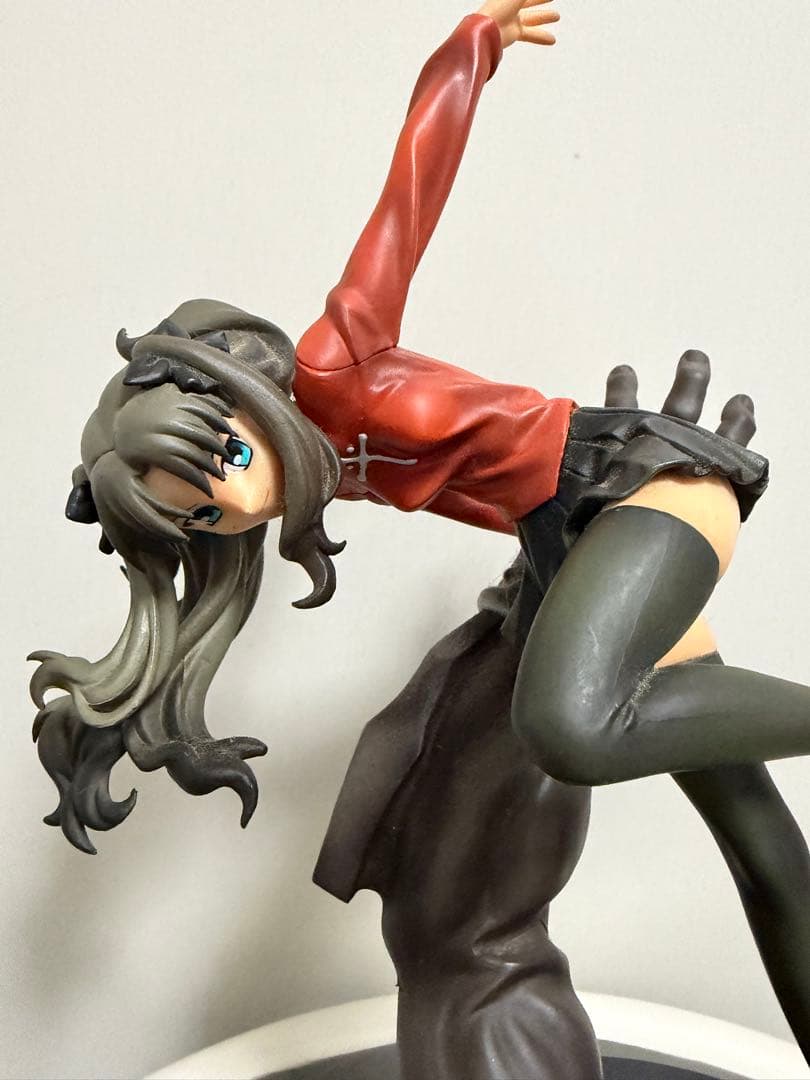 A close-up of a Tohsaka Rin figure posed with one arm raised on a plain light background.