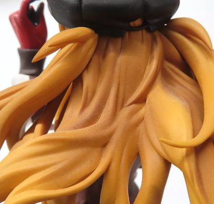 Close-up of a figure’s orange hair and red hand against a white background.