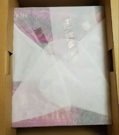 A boxed figure package inside a brown shipping box, covered with white tissue paper.