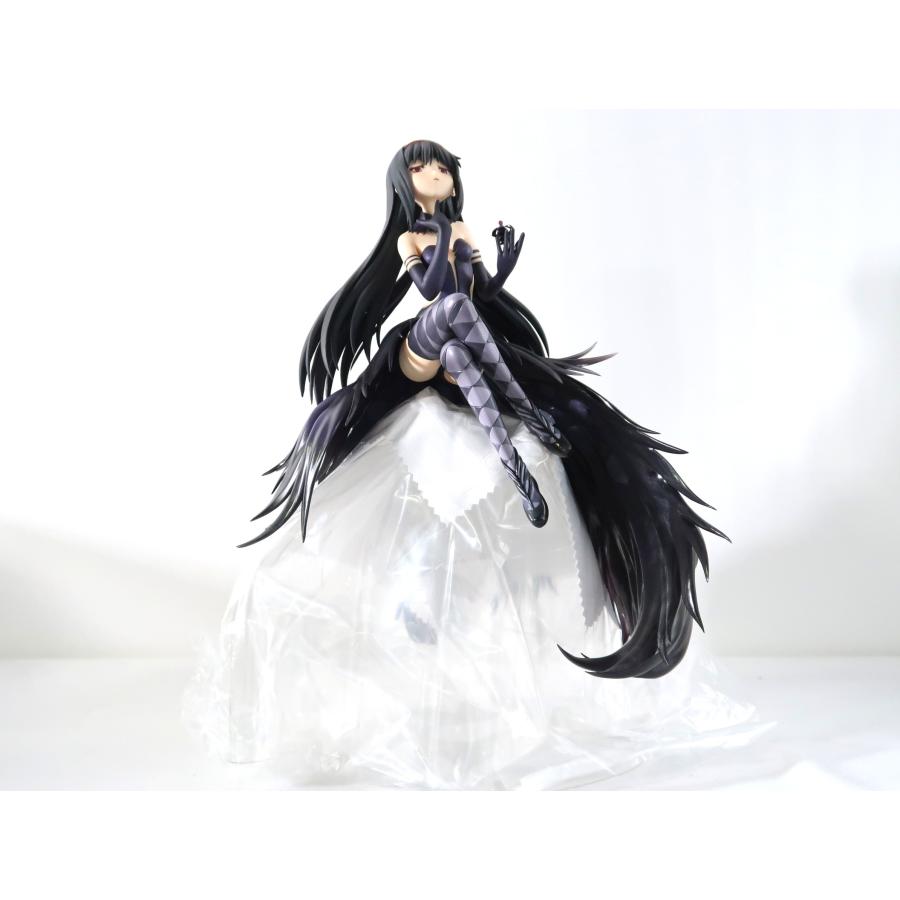 A black-haired anime figure sitting on a white translucent plastic cover against a plain white background.