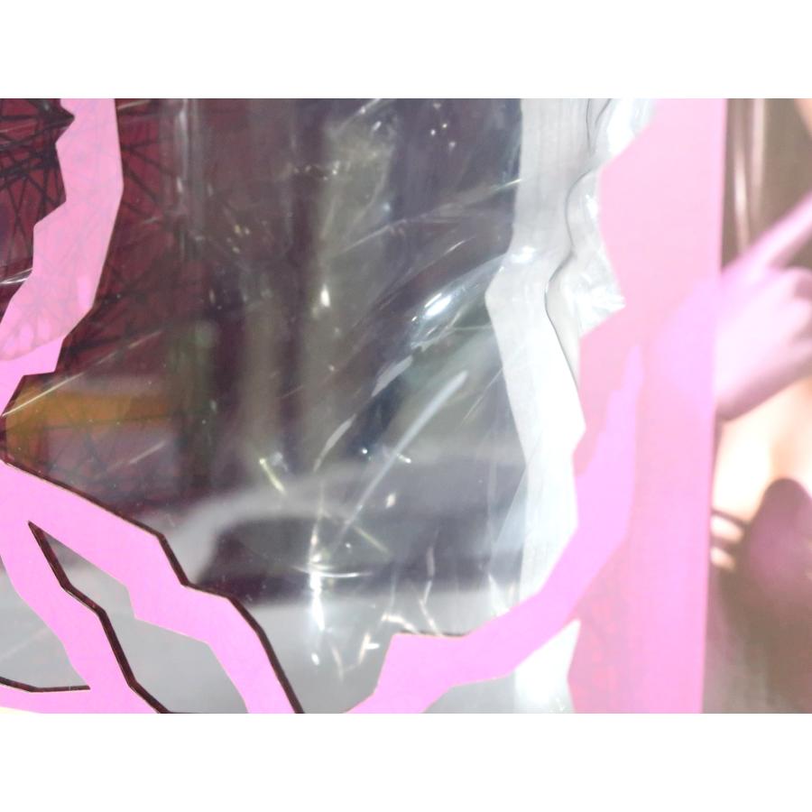 Close-up through a clear plastic window of a boxed figure with pink printed packaging.