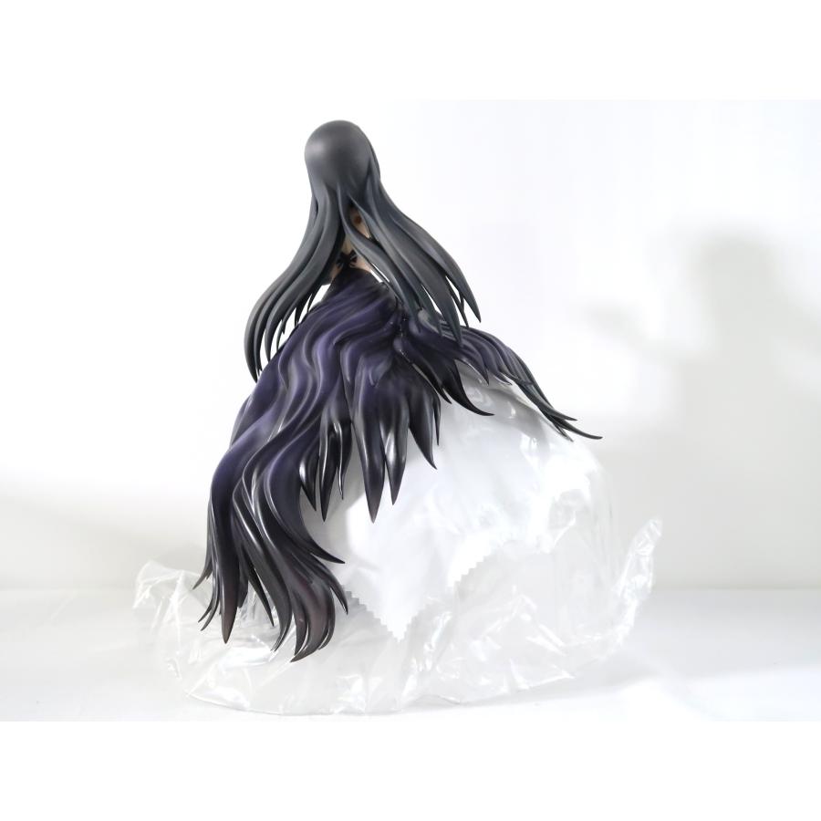 A black-haired figure with flowing purple-black hair seen from the back on a white surface.