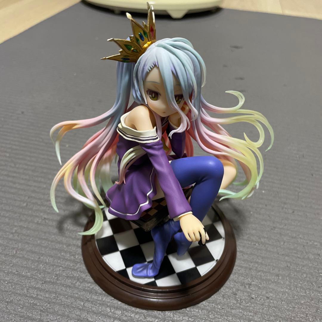 A seated anime figure with long pastel hair and a crown on a checkered round base.