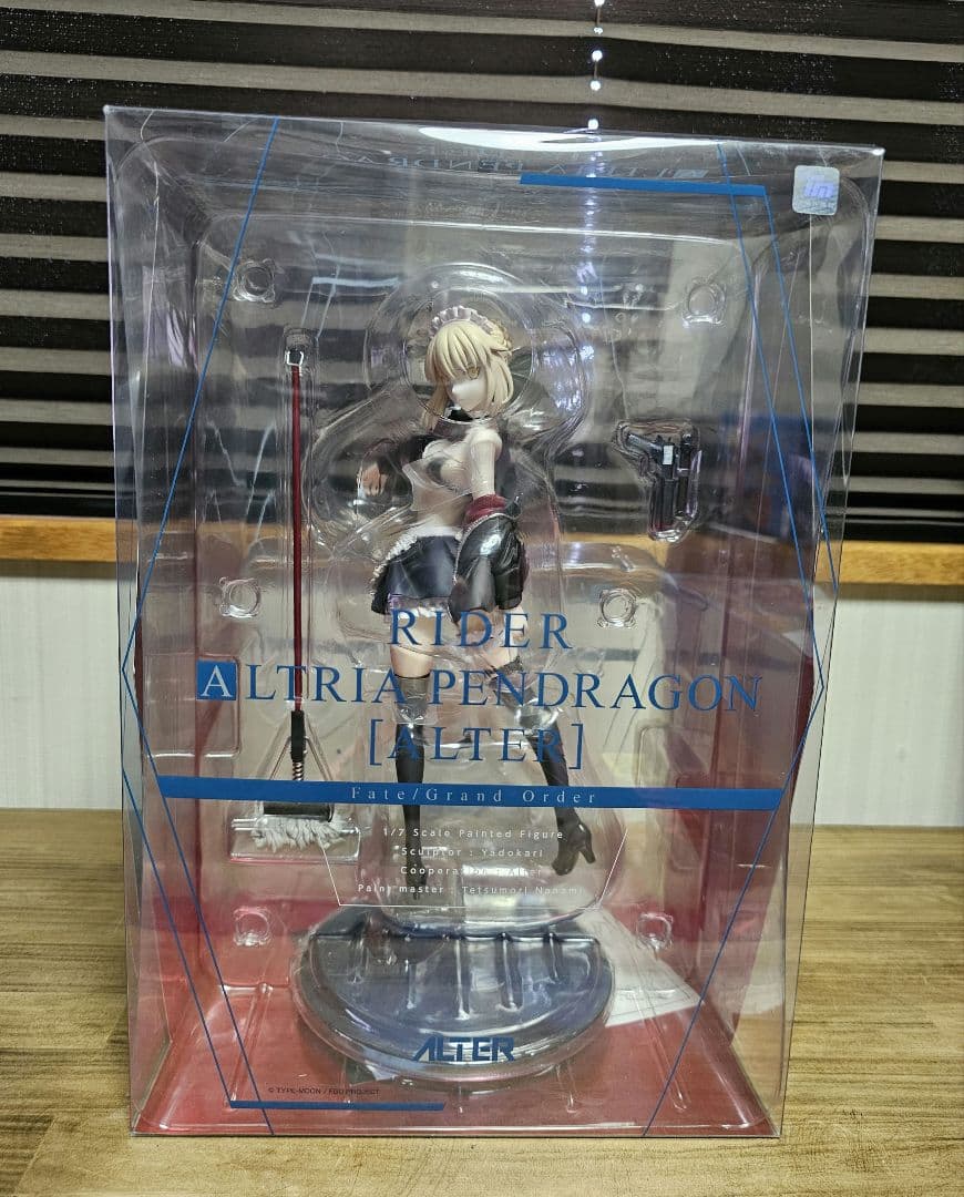 A boxed figure of Altria Pendragon Alter with accessory parts and stand visible through the window.