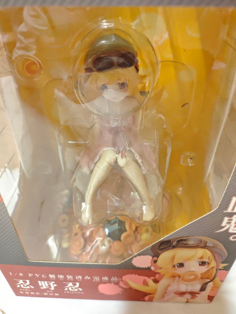 A boxed anime figure is visible through a clear plastic window with yellow backing.