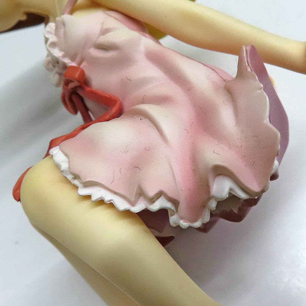 Close-up of a pink dress and pale legs of a figure on a white background.