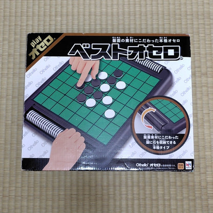 A boxed Othello board game shown from the front on a tatami mat.