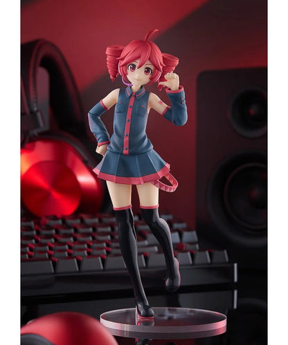 Red-haired anime figure in blue uniform posing on clear base, with headphones, speakers and keyboard behind