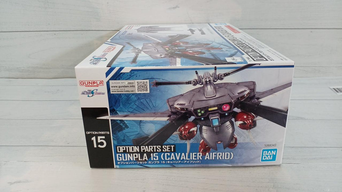 Gunpla Option Parts Set 15 Cavalier Aifrid retail box on a pale wood surface, with front and top visible.
