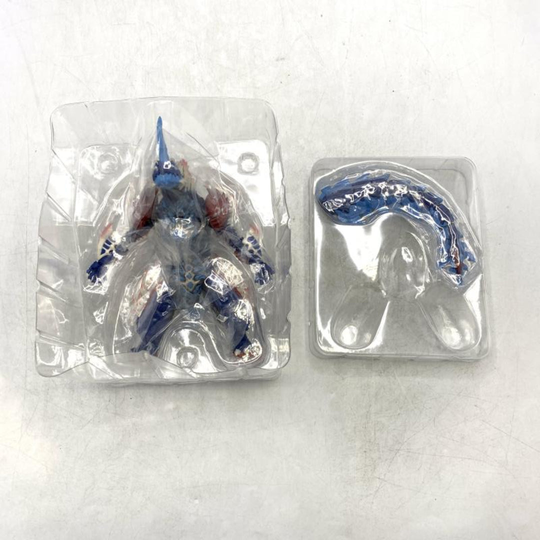 Blue and red horned monster figure in a clear inner blister, with a detached tail in a separate tray.
