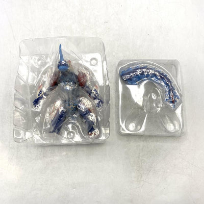Blue and red horned monster figure in a clear inner blister, with a detached tail in a separate tray.