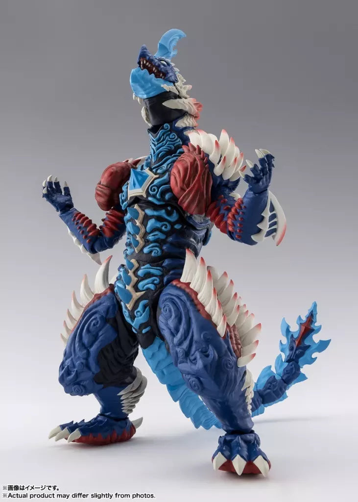 Blue and red horned monster figure with white spikes, raised claws, and a long tail on a studio background.