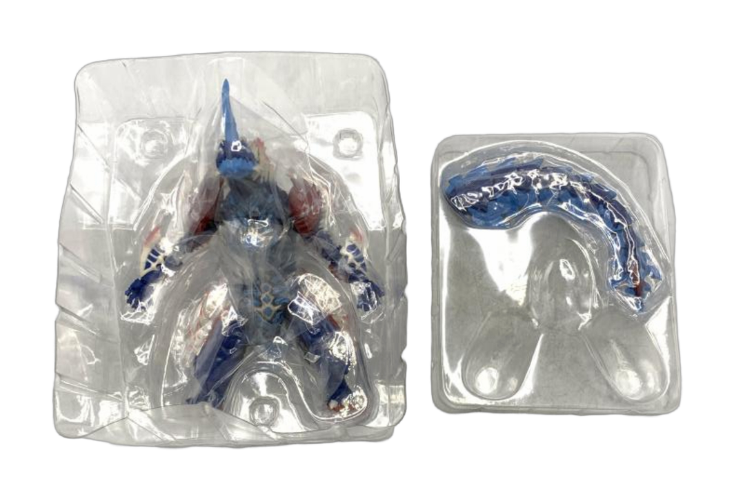 Blue and red horned monster figure in a clear inner blister, with a detached tail in a separate tray. (cut-out)