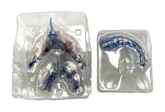 Blue and red horned monster figure in a clear inner blister, with a detached tail in a separate tray. (cut-out)
