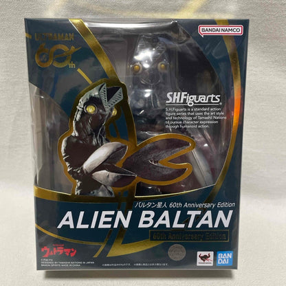 Front of a boxed S.H.Figuarts Alien Baltan 60th Anniversary Edition figure on a textured fabric surface.
