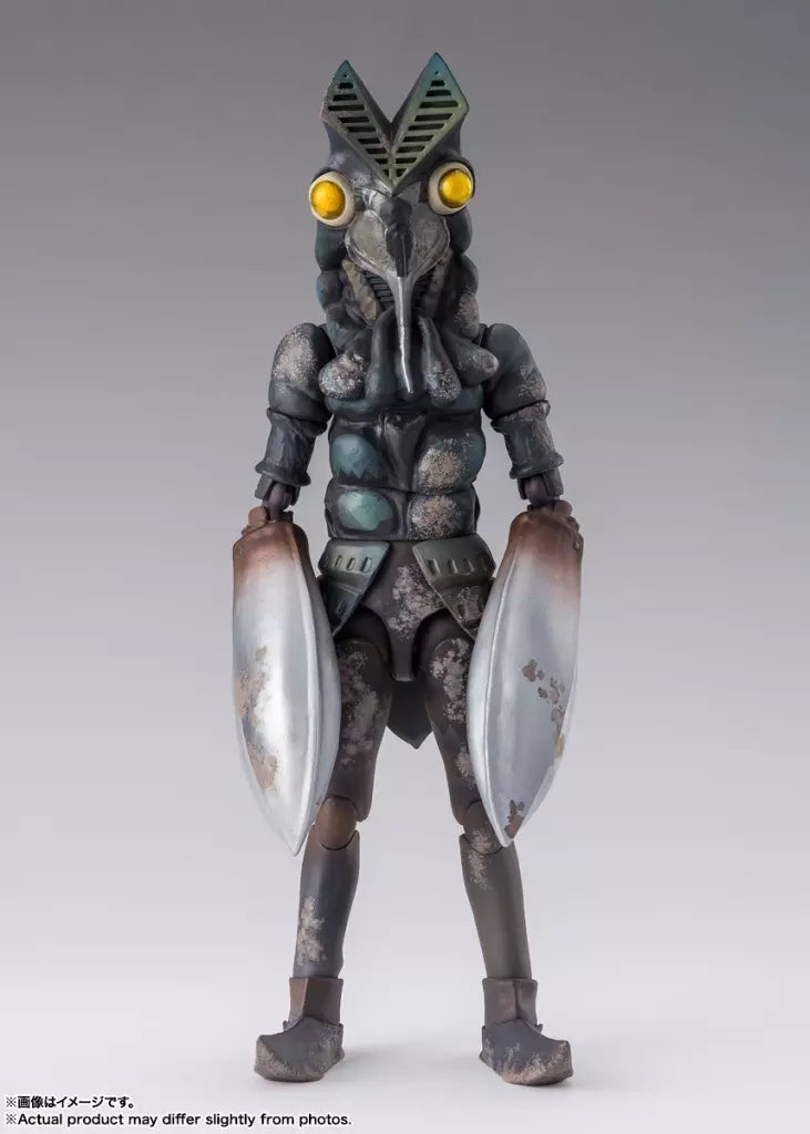 Front view of Alien Baltan figure with yellow eyes, silver claws, and mottled dark body on a gray background.