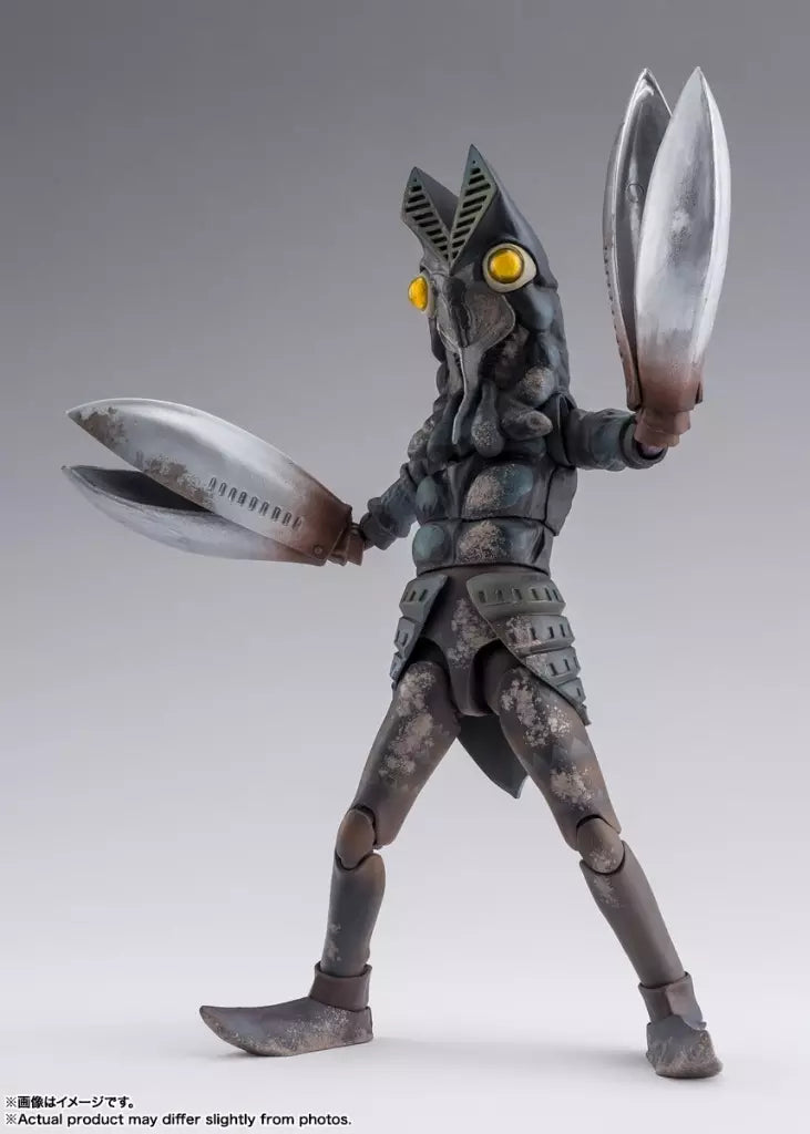 Alien Baltan figure with yellow eyes and large silver claws posed with arms raised on a gray background.
