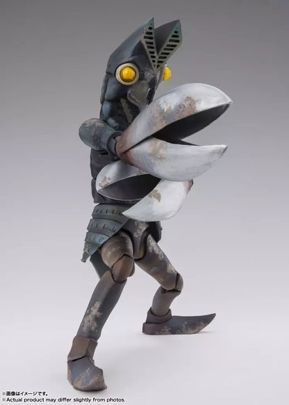 Alien Baltan figure in a side-facing pose with yellow eyes, large open claws, and weathered paint.