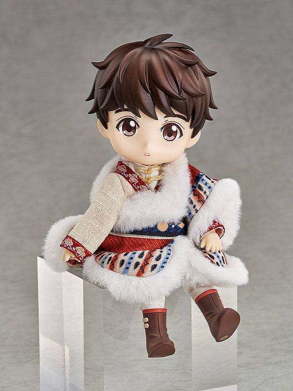 Brown-haired doll in a patterned, white fur-trimmed outfit and brown boots, seated on a clear block.
