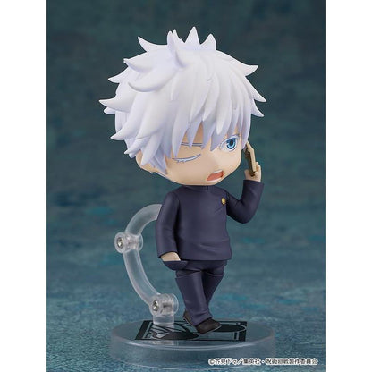 White-haired Gojo figure in a dark school uniform holding a phone, on a clear stand against a teal backdrop.