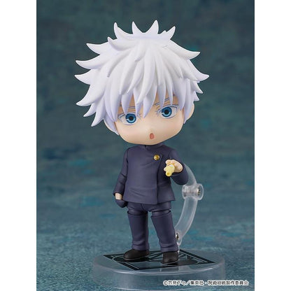 White-haired Gojo figure in a dark school uniform holding a snack, on a clear base against a teal backdrop.