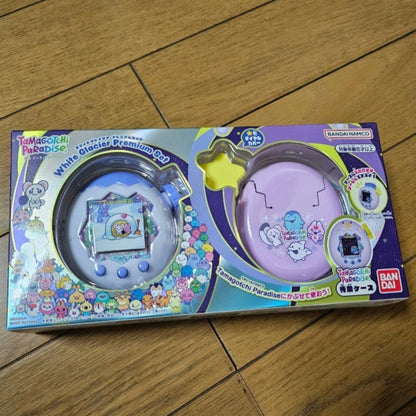 A boxed Tamagotchi Paradise White Glacier Premium Set on a wooden floor.